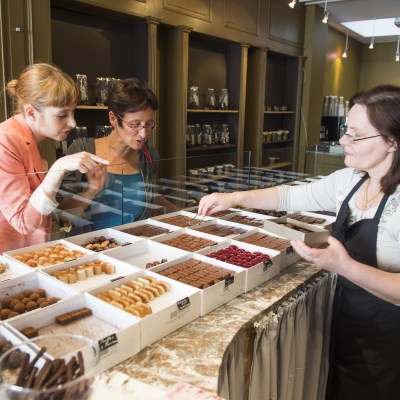A saleswoman is helping two female clients picking chocolates in a chocolate store in Brussels, Belgium