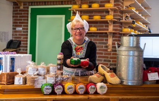Woman in traditional clothing offering cheese in a cheese farm in Amsterdam, the Netherlands/Holland